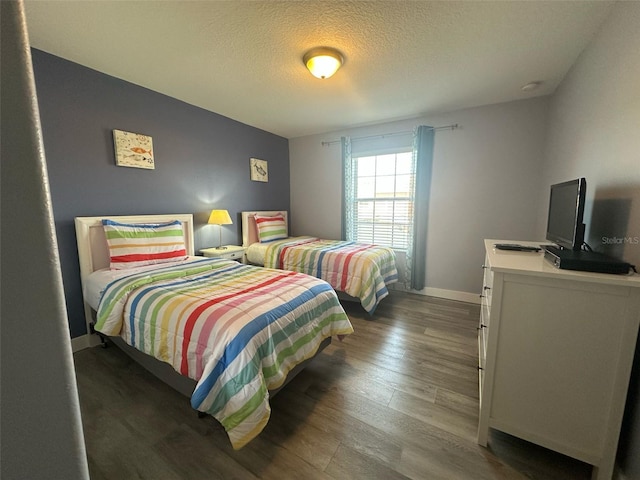 bedroom featuring a textured ceiling, baseboards, and wood finished floors