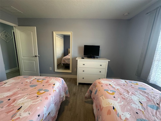 bedroom featuring a textured ceiling, baseboards, and wood finished floors