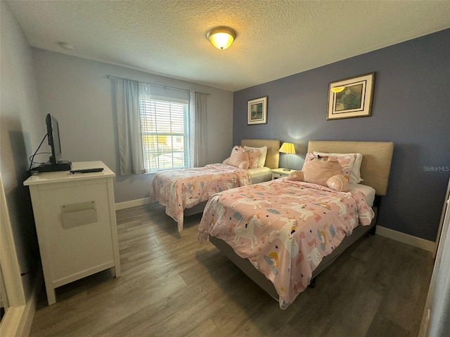 bedroom with a textured ceiling, baseboards, and wood finished floors