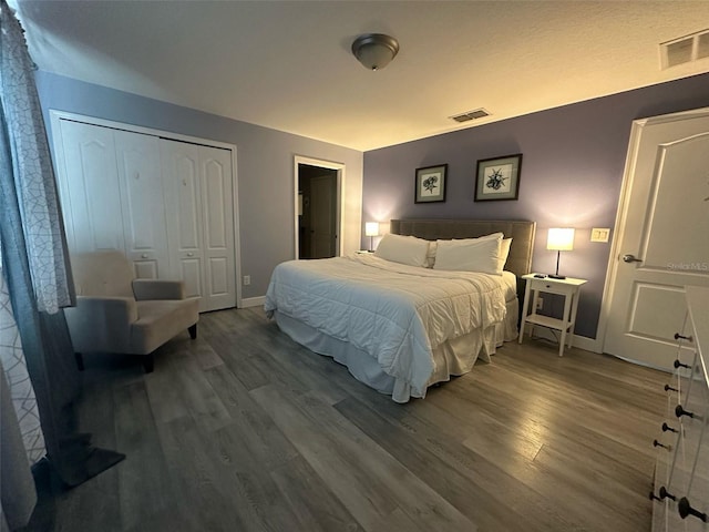 bedroom featuring baseboards, a closet, visible vents, and wood finished floors