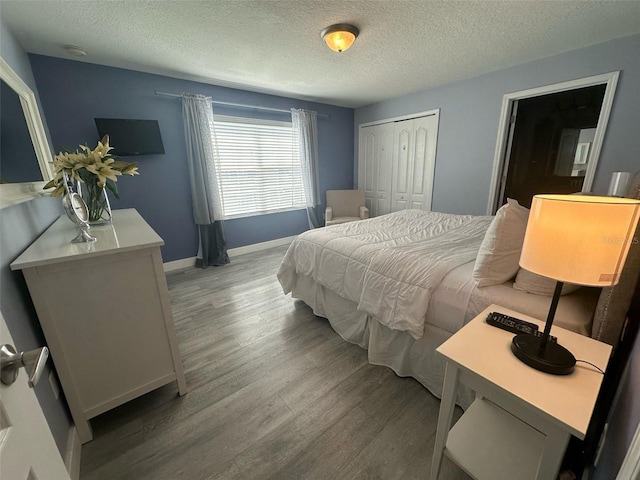 bedroom with a textured ceiling, a closet, baseboards, and wood finished floors