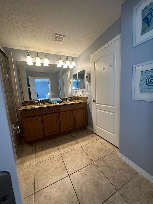 full bathroom with a textured ceiling, tile patterned flooring, a shower with shower door, visible vents, and double vanity