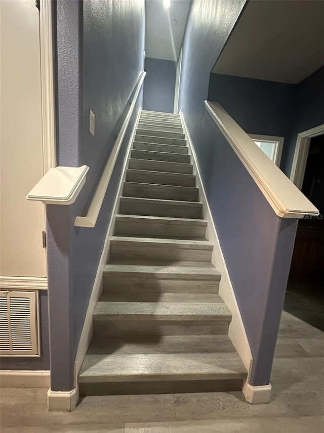 stairs with visible vents and wood finished floors