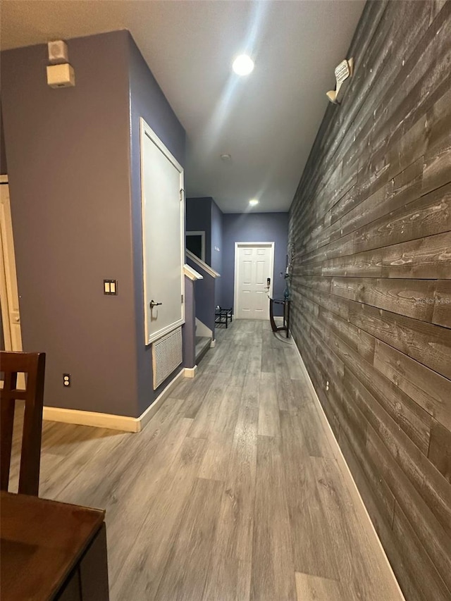 corridor with wooden walls, baseboards, and wood finished floors