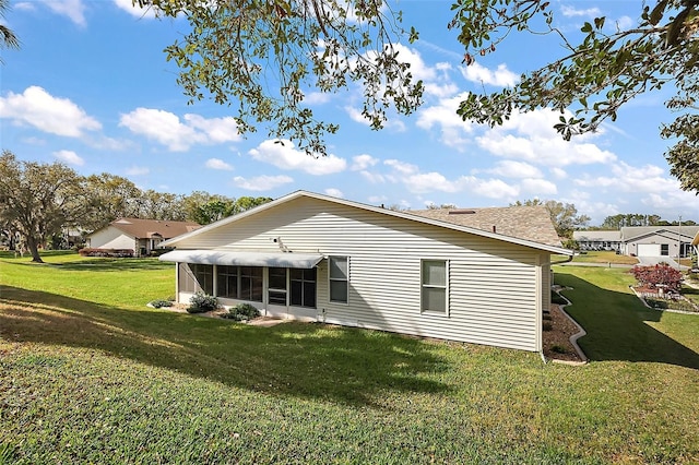 rear view of property featuring a sunroom and a yard