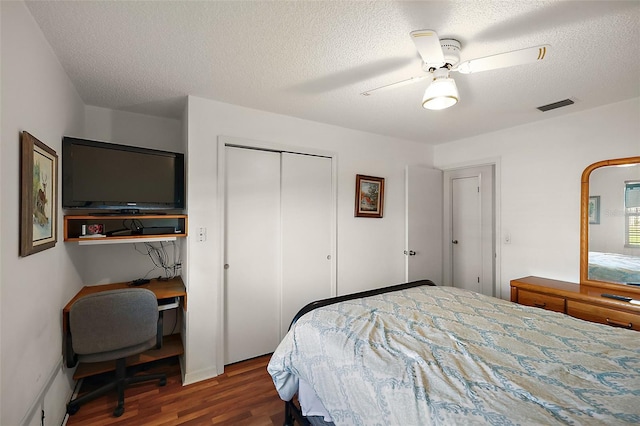 bedroom with a textured ceiling, a closet, visible vents, and wood finished floors