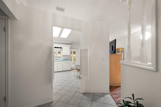 hallway with visible vents, baseboards, and light tile patterned floors