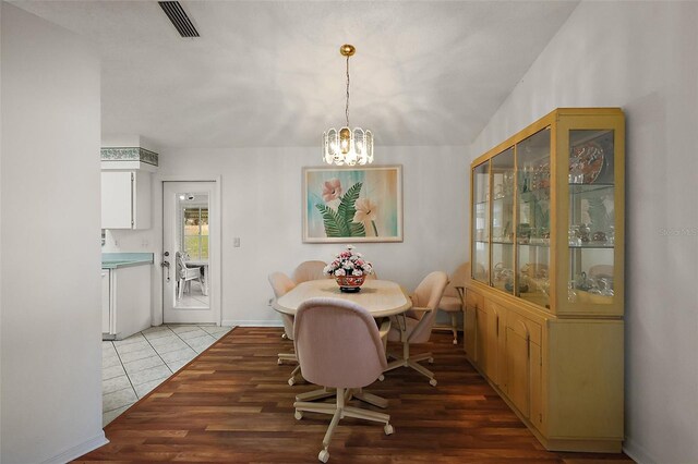 dining space with a notable chandelier, baseboards, visible vents, and light wood-style floors