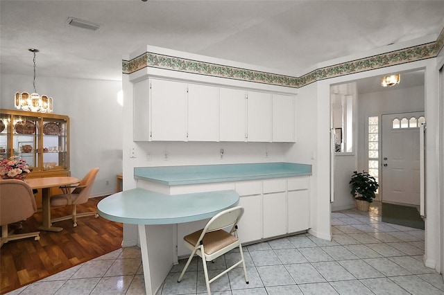 kitchen with light tile patterned floors, baseboards, a chandelier, light countertops, and white cabinetry