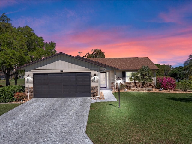 view of front of house featuring stone siding, an attached garage, decorative driveway, and a front yard