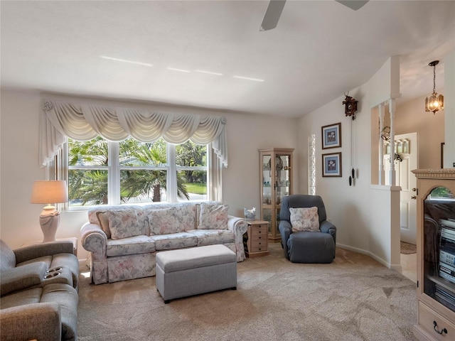 carpeted living area with ceiling fan with notable chandelier, baseboards, and vaulted ceiling