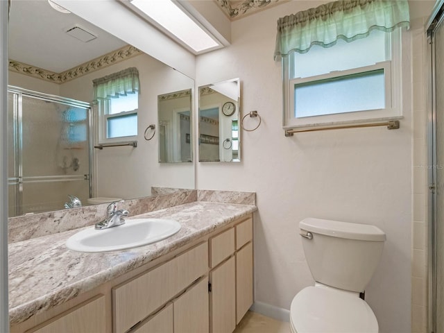 full bathroom featuring vanity, baseboards, a skylight, a stall shower, and toilet