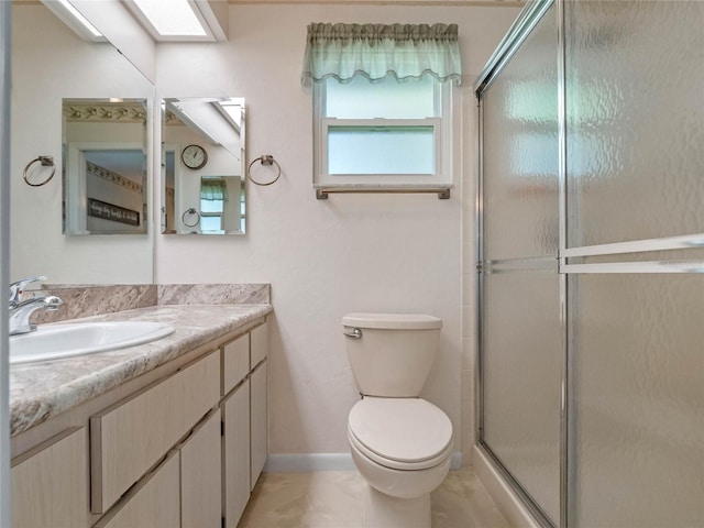 bathroom featuring a skylight, a stall shower, toilet, and vanity