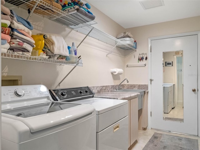 laundry room featuring laundry area, washing machine and dryer, visible vents, and a sink