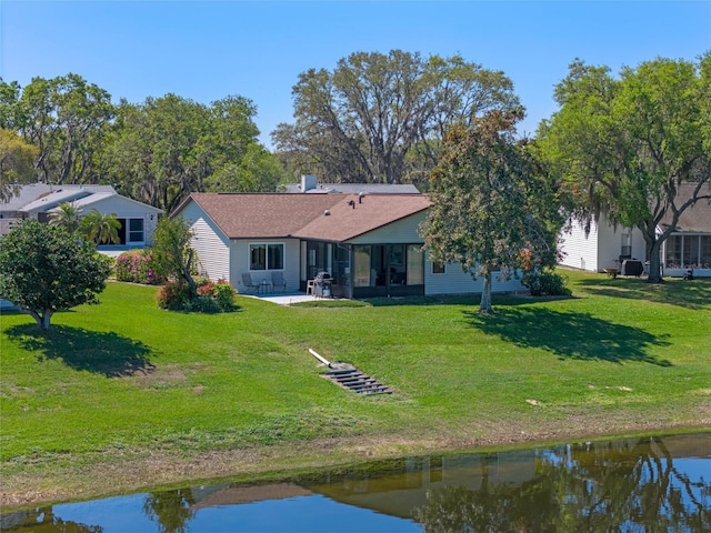 back of property featuring a water view, a lawn, and a patio area