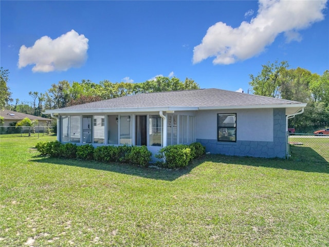 ranch-style house featuring a front yard, fence, roof with shingles, and stucco siding