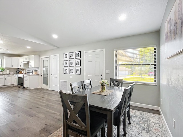 dining space with recessed lighting, baseboards, dark wood-type flooring, and a textured ceiling