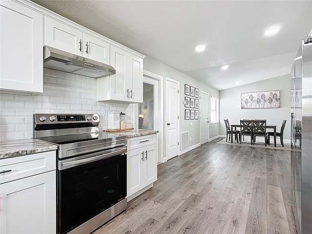 kitchen featuring vaulted ceiling, stainless steel range with electric stovetop, light wood-style floors, under cabinet range hood, and tasteful backsplash