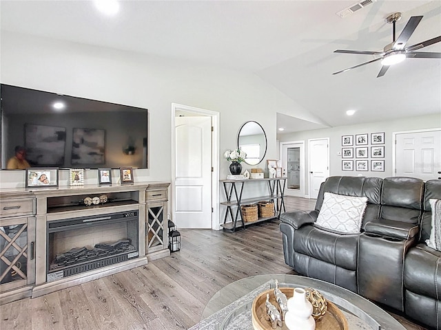 living area with vaulted ceiling, visible vents, ceiling fan, and wood finished floors