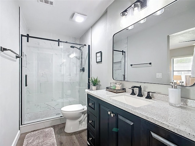 full bath with visible vents, toilet, wood finished floors, a shower stall, and vanity