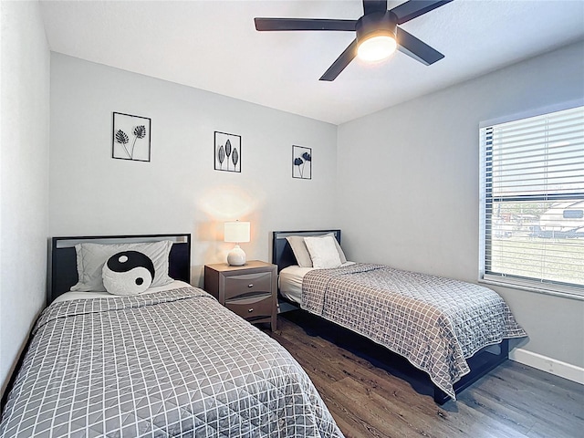 bedroom with a ceiling fan, baseboards, and wood finished floors