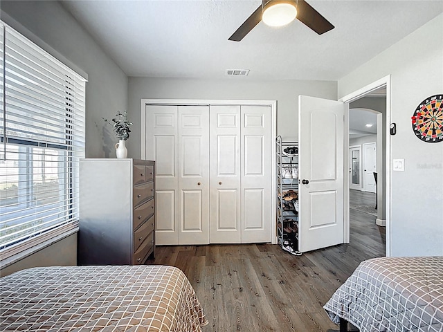 bedroom featuring visible vents, a closet, arched walkways, ceiling fan, and dark wood-style flooring