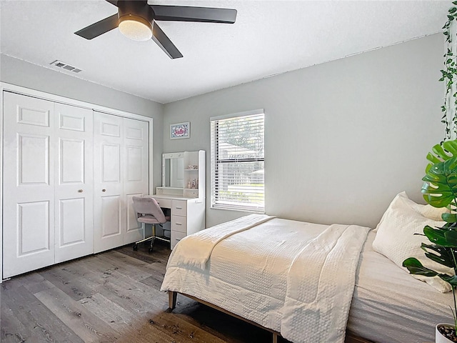 bedroom featuring visible vents, a closet, wood finished floors, and a ceiling fan