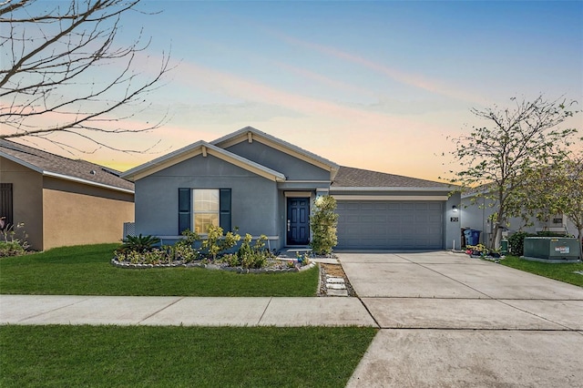 ranch-style house with driveway, a front yard, an attached garage, and stucco siding