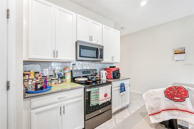 kitchen featuring light tile patterned floors, tasteful backsplash, light countertops, appliances with stainless steel finishes, and white cabinets