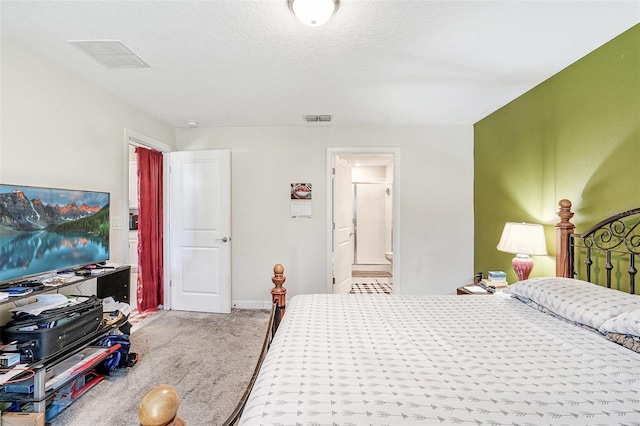 carpeted bedroom featuring baseboards, ensuite bath, visible vents, and a textured ceiling