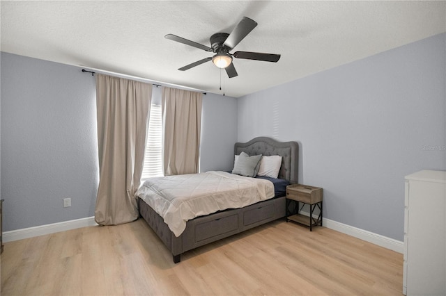 bedroom featuring baseboards, ceiling fan, a textured ceiling, and light wood finished floors