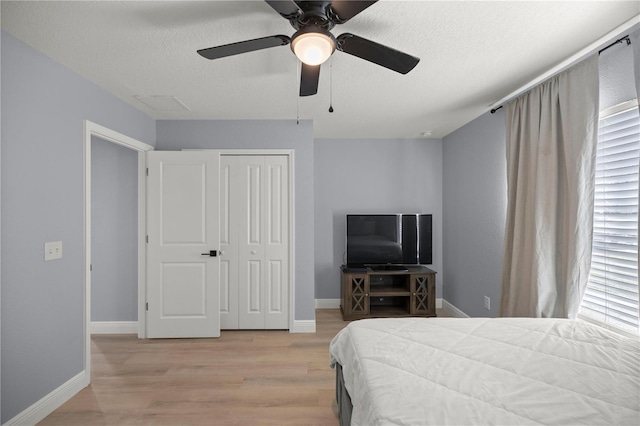 bedroom featuring a textured ceiling, baseboards, visible vents, and light wood-style floors