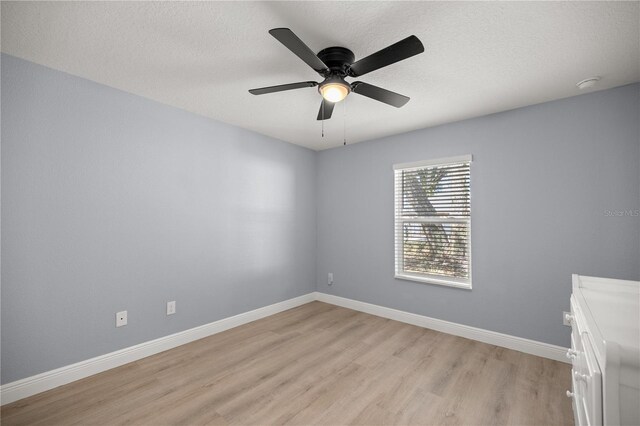 spare room with a ceiling fan, baseboards, a textured ceiling, and light wood finished floors