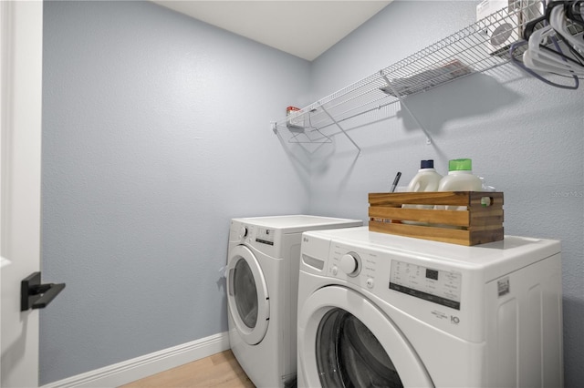 laundry area featuring baseboards, laundry area, light wood-type flooring, and washer and dryer