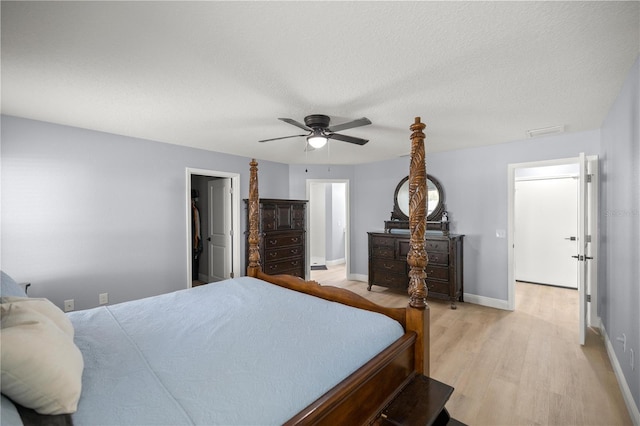 bedroom featuring baseboards, visible vents, a ceiling fan, a textured ceiling, and light wood-style floors