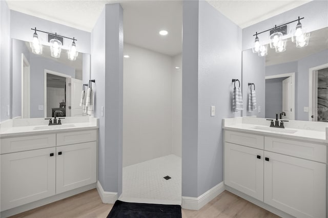 bathroom featuring wood finished floors, two vanities, and a sink