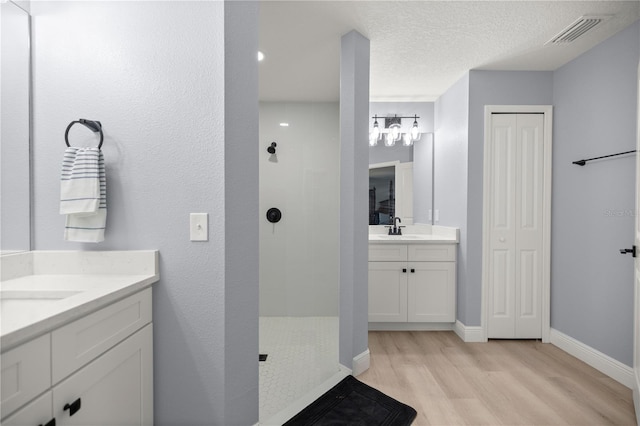 bathroom with two vanities, visible vents, a sink, and a walk in shower