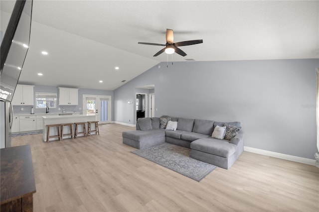 living room featuring light wood finished floors, visible vents, baseboards, and vaulted ceiling