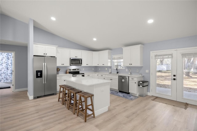 kitchen with a center island, stainless steel appliances, light countertops, white cabinets, and a sink