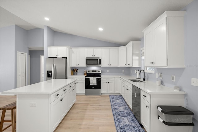 kitchen with a kitchen island, vaulted ceiling, stainless steel appliances, light wood-type flooring, and a sink