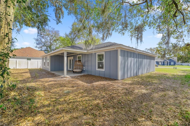 rear view of property with fence, board and batten siding, and a patio