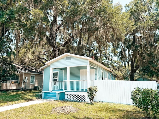 view of front of property featuring a porch, fence, and a front lawn