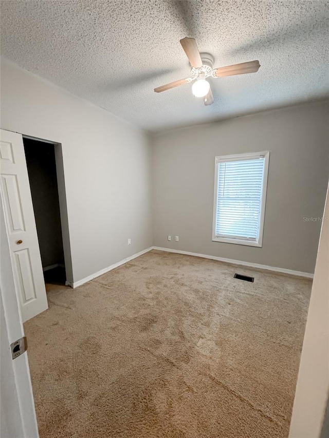 unfurnished bedroom with visible vents, baseboards, ceiling fan, a textured ceiling, and carpet floors