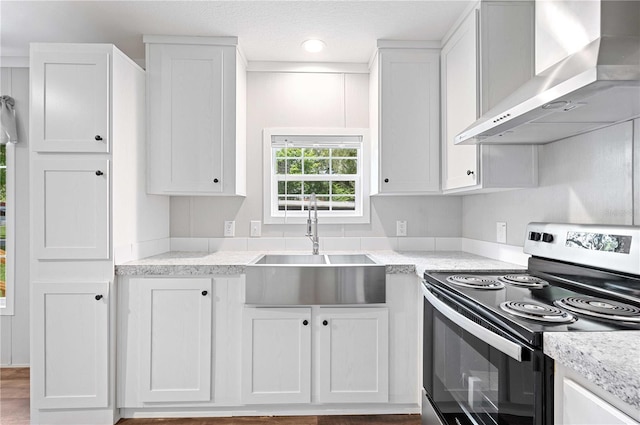 kitchen with wall chimney exhaust hood, a sink, white cabinets, and stainless steel electric stove