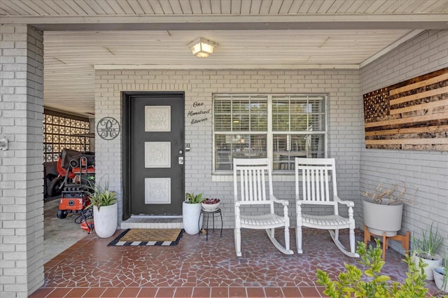 property entrance featuring brick siding and covered porch