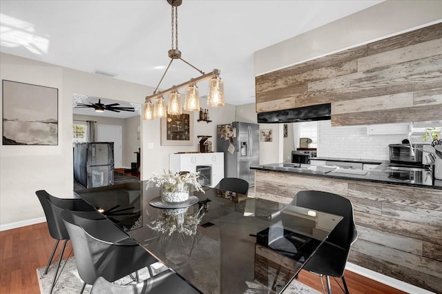 dining room featuring wood finished floors, a fireplace, baseboards, and ceiling fan