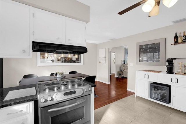 kitchen featuring white cabinetry, exhaust hood, stainless steel electric range, and light tile patterned floors