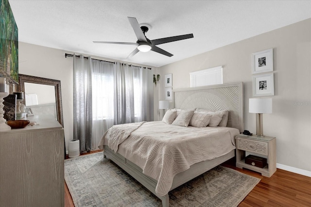 bedroom with ceiling fan, baseboards, and wood finished floors