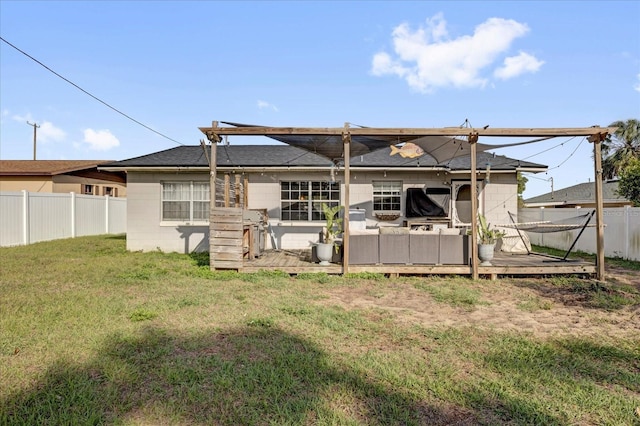 back of house with a yard, a deck, concrete block siding, and a fenced backyard