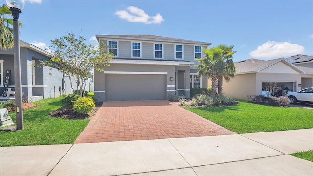 traditional-style home featuring decorative driveway, an attached garage, a front yard, and stucco siding